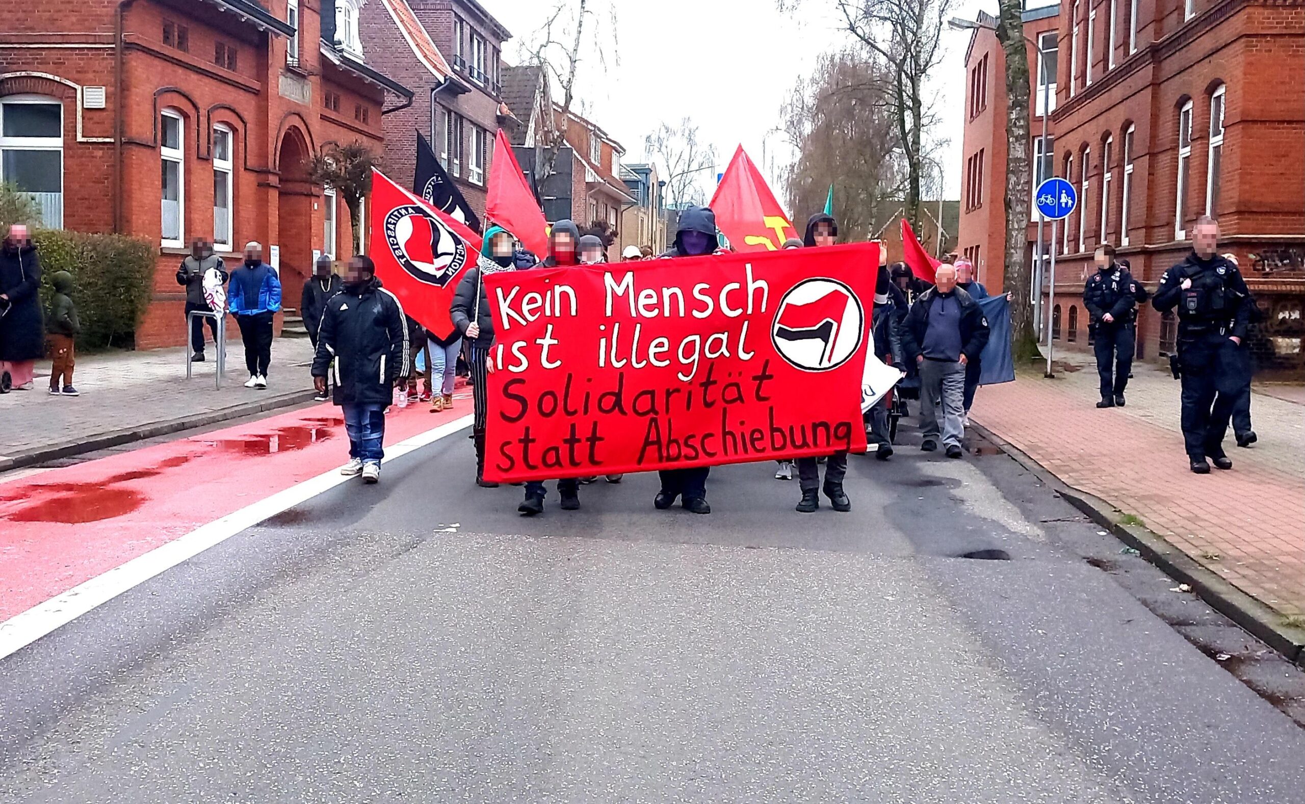 Das Bild zeigt die Demonstration von vorne mit großem Banner und der Aufschrift "Kein Mensch ist illegal - Solidarität statt Abschiebung"